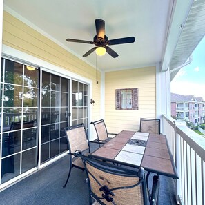 An outdoor patio with a table and chairs, a ceiling fan, and a view of a residential area. - Pet Friendly 2BR Condo, Spacious w/ Vaulted Ceilings! (Little River)