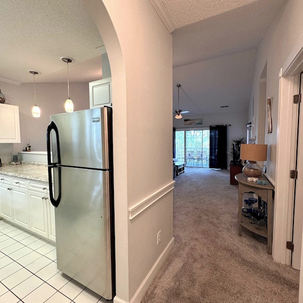 A kitchen with a stainless steel refrigerator, white cabinets, and a tiled backsplash.