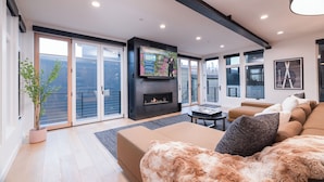 A modern living room with a fireplace, a large flat-screen TV, and a comfortable sofa. - Modern Old Town Home by InvitedHome | Ski-In/Out, Walk to Town, Hot Tub (Park City)