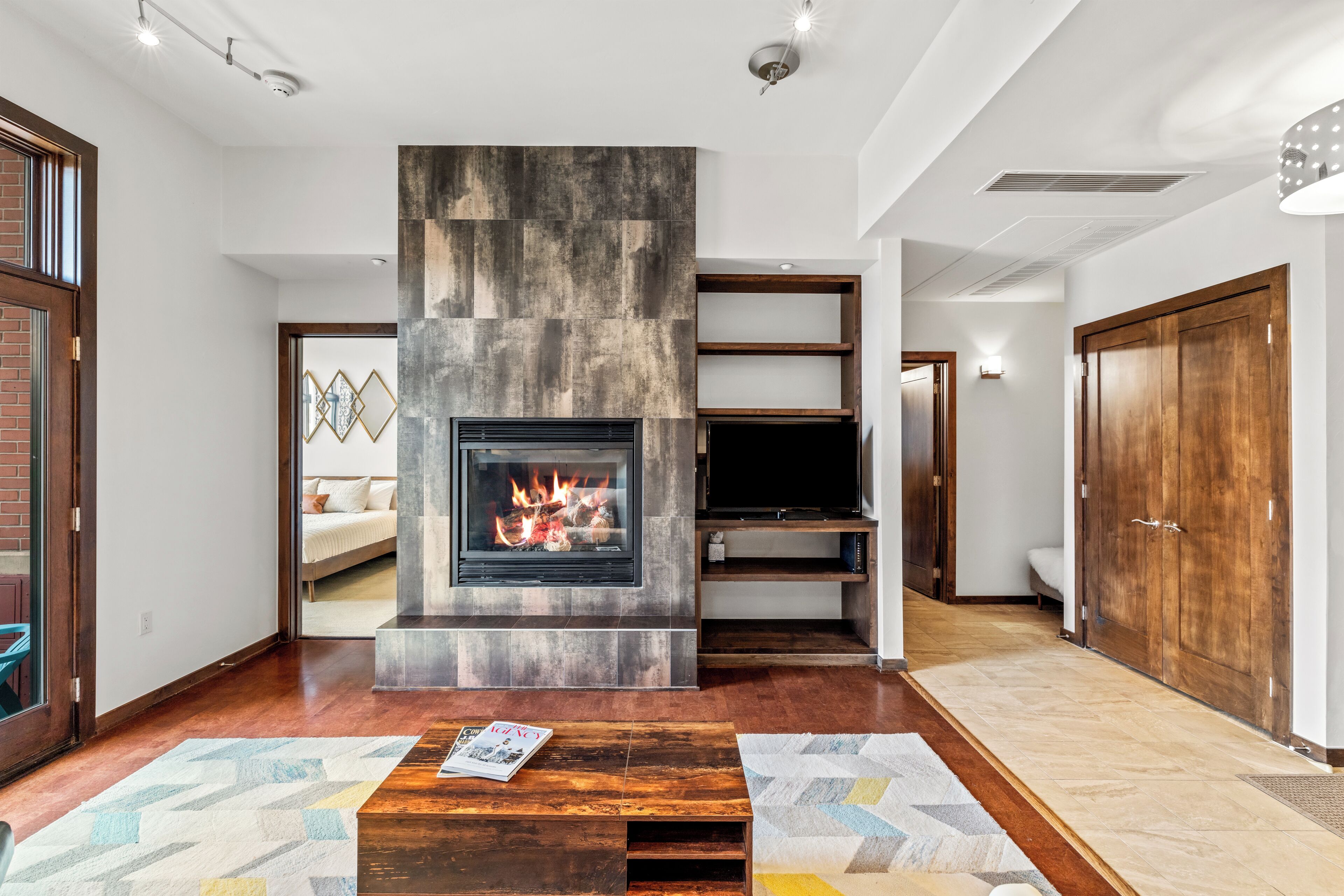 Ein modernes Wohnzimmer mit Kamin, Holzboden und einer TV-Konsole.