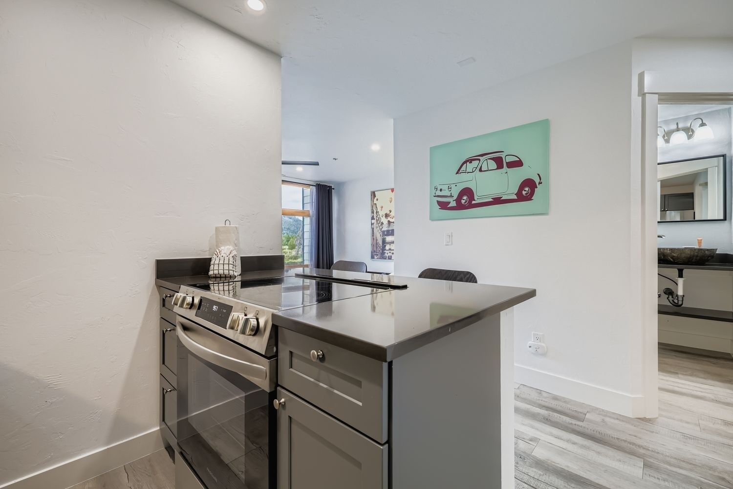 A modern kitchen with stainless steel appliances, a dining area with a table and chairs, and a view of the outdoors.