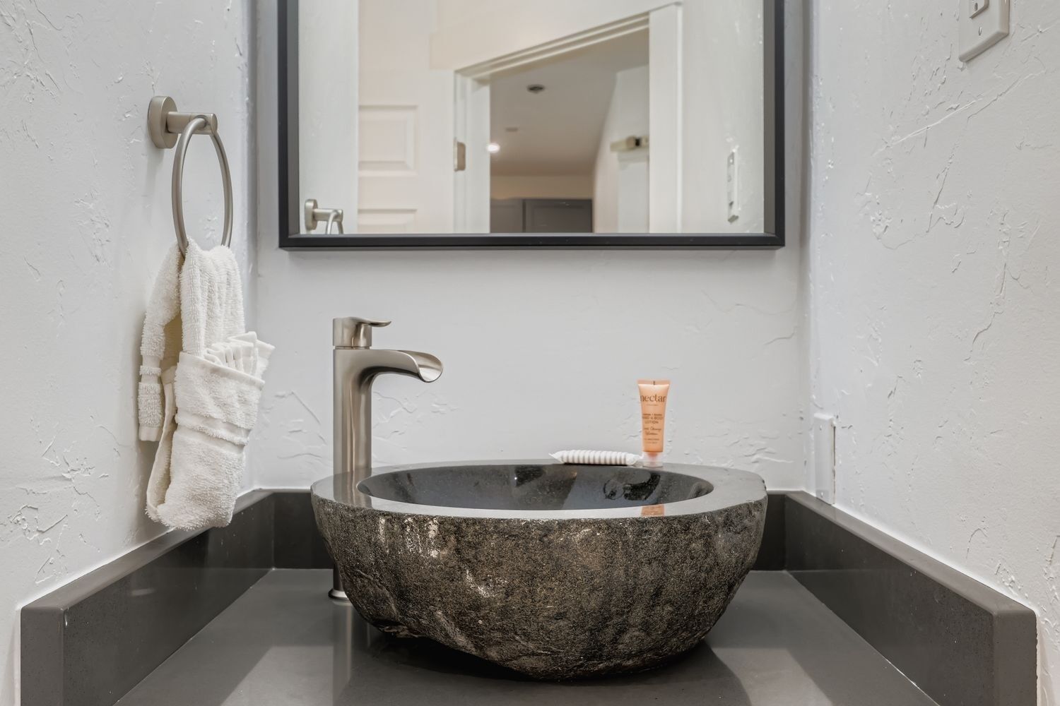 Un bagno con un lavabo in pietra, un rubinetto moderno e un porta asciugamani.