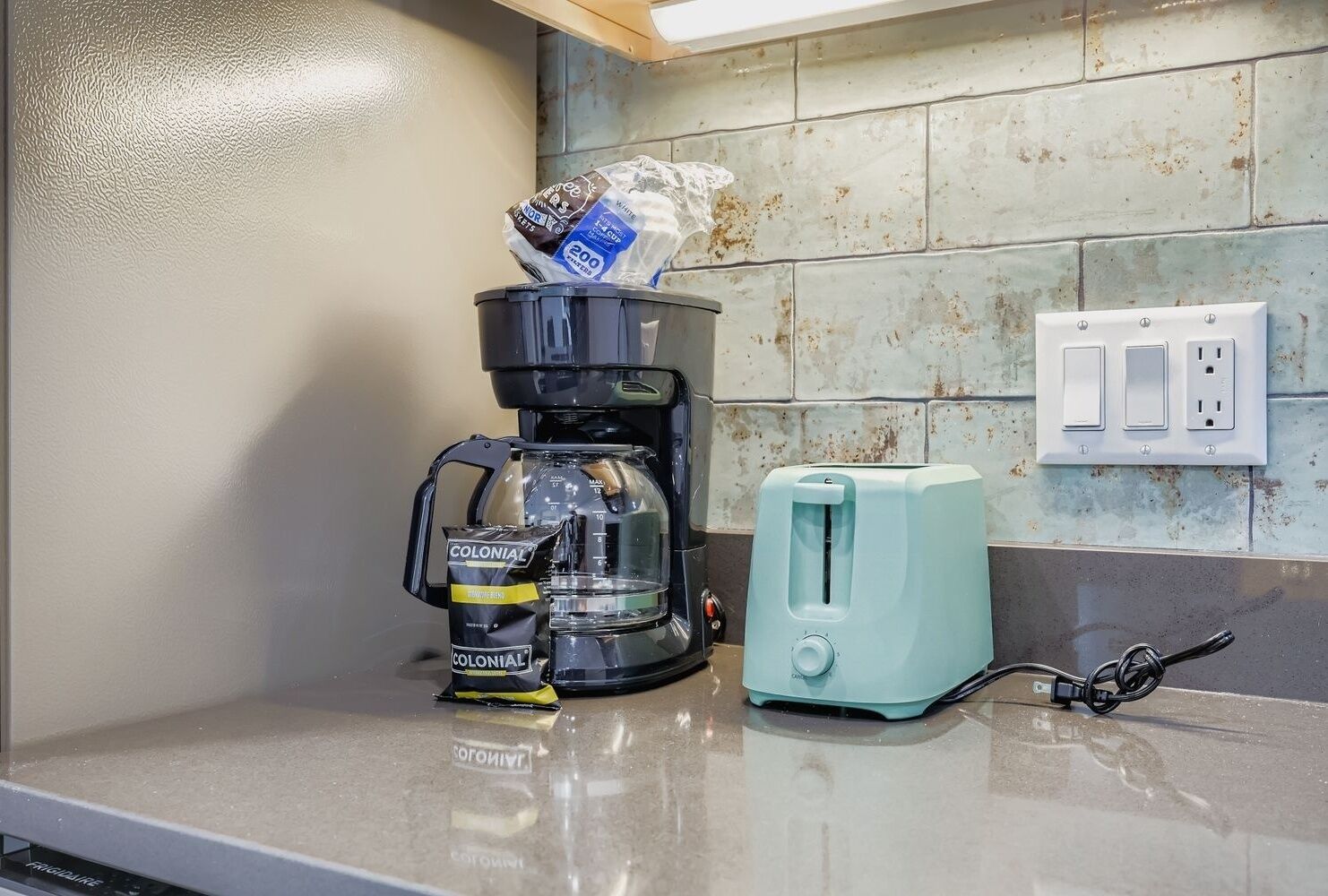 A kitchen with a coffee maker, a toaster, and a bag of coffee.