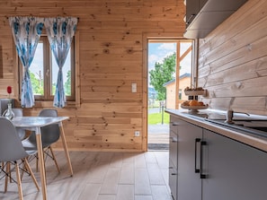 Un intérieur en bois comprenant un coin repas, une cuisine et une vue sur l’extérieur.