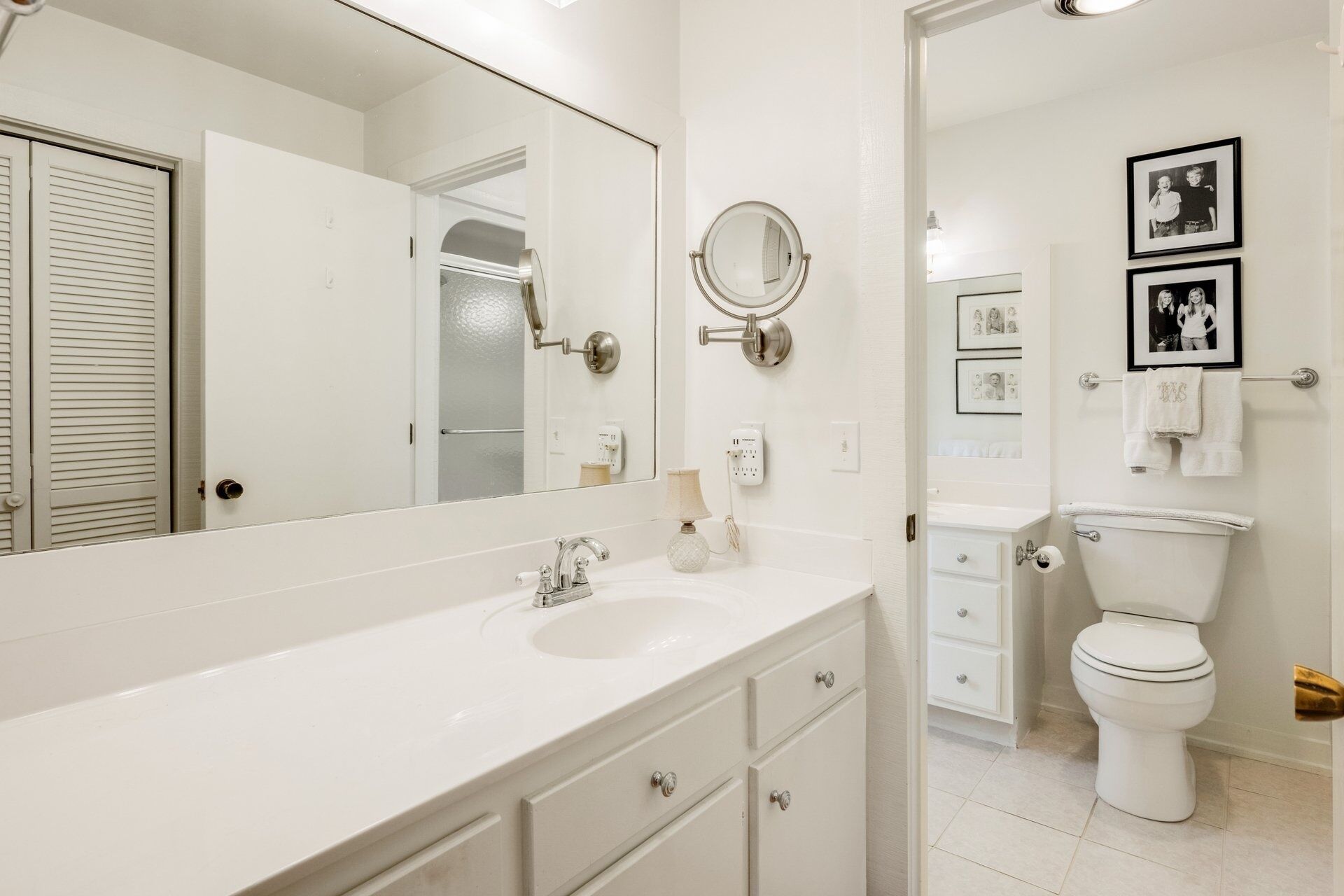 A modern bathroom with a large mirror, a sink, a toilet, and a vanity with drawers.
