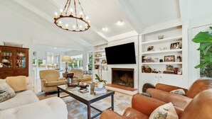 A spacious living room with a fireplace, comfortable seating, and a television mounted on the wall. - Sunny Pointe 4 Bedroom Home (Georgetown)