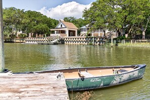 A green boat docked at a wooden pier, a house with a porch, and a tree-lined waterfront. - Sunny Pointe 4 Bedroom Home (Georgetown)