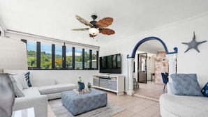 Una sala de estar moderna con un televisor grande, asientos cómodos y vistas al exterior.