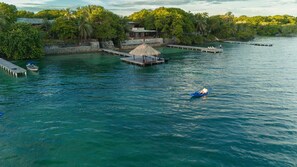 Une zone côtière comprenant un quai, une construction à toit de chaume et un petit bateau.