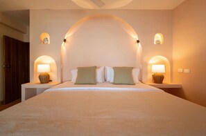 Une chambre d’hôtel avec un grand lit, deux lampes de chevet et un mur aux lignes courbes.