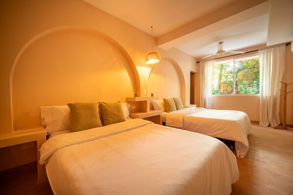 Une chambre d’hôtel avec deux lits, un ventilateur de plafond et une fenêtre avec des rideaux.