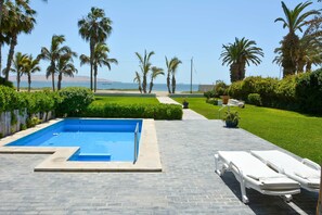 A swimming pool with lounge chairs, palm trees, and a view of the ocean. - w Modern 5BR With Private Pool in Paracas (Paracas)