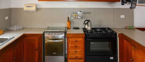 Een keuken met twee ovens, een houten kast en een koffiezetapparaat.