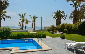 A swimming pool with a view of the sea, surrounded by palm trees and a grassy area. - w Modern 5BR With Private Pool in Paracas (Paracas)