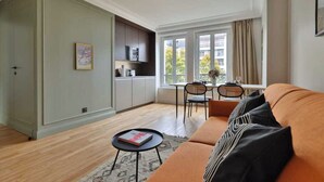 A modern living room with a sofa, a coffee table, and a dining area with a table and chairs. - Modern Apartment - 1br/4p - Canal St-martin (Paris)