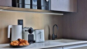 A modern kitchen with a built-in toaster, a coffee maker, and a sink. - Modern Apartment - 1br/4p - Canal St-martin (Paris)