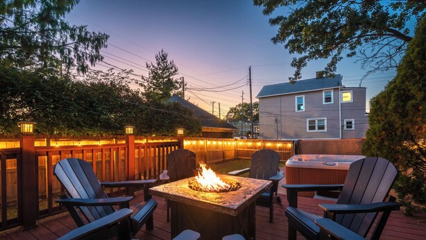 An outdoor deck with a fire pit, Adirondack chairs, and a hot tub. - The Reserve ~ 5BR Fun! Hot Tub, Fire Pit, Deck, Walkable To Bardstown Rd (Louisville)