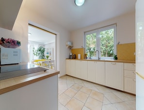 A modern kitchen with white cabinetry, a built-in oven, and a window providing a view of greenery outside.