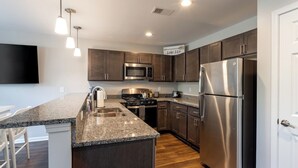 A modern kitchen with granite countertops, stainless steel appliances, and dark wooden cabinets. - Lakeside Bliss- Close to Highmark Stadium, home of the Bills! (Angola)