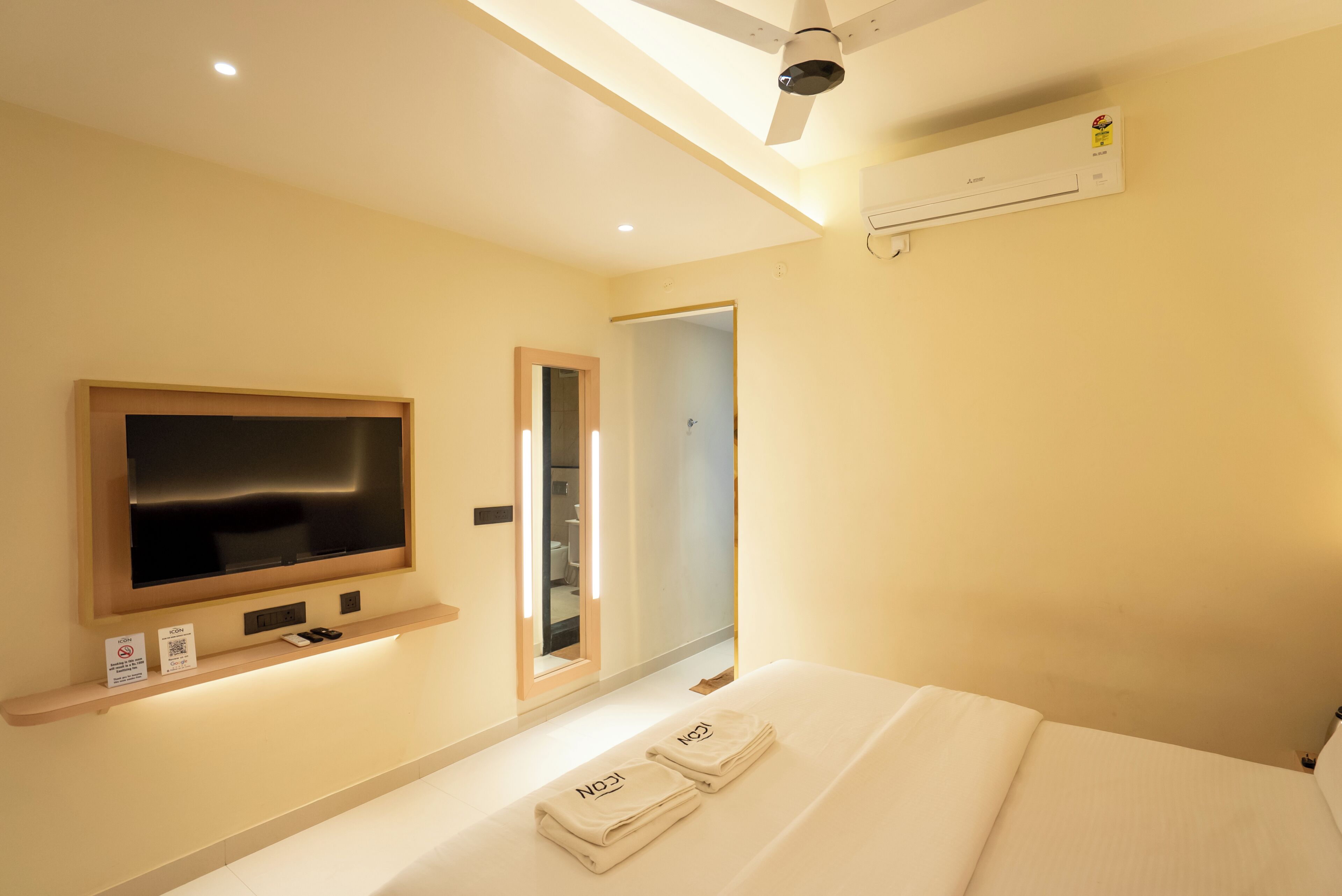 Une chambre d’hôtel équipée d’un lit, d’une télévision, d’un ventilateur de plafond, d’un climatiseur et d’un miroir.