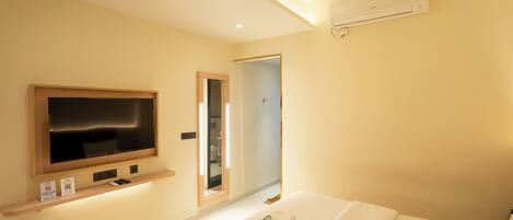 Une chambre d’hôtel équipée d’un lit, d’une télévision, d’un ventilateur de plafond, d’un climatiseur et d’un miroir.