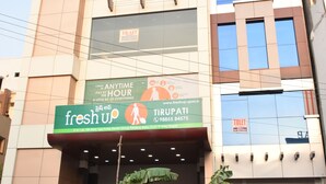 Un edificio de varios pisos con una planta baja comercial que muestra un letrero que dice 'fresh up', un baño visible y scooters estacionados.