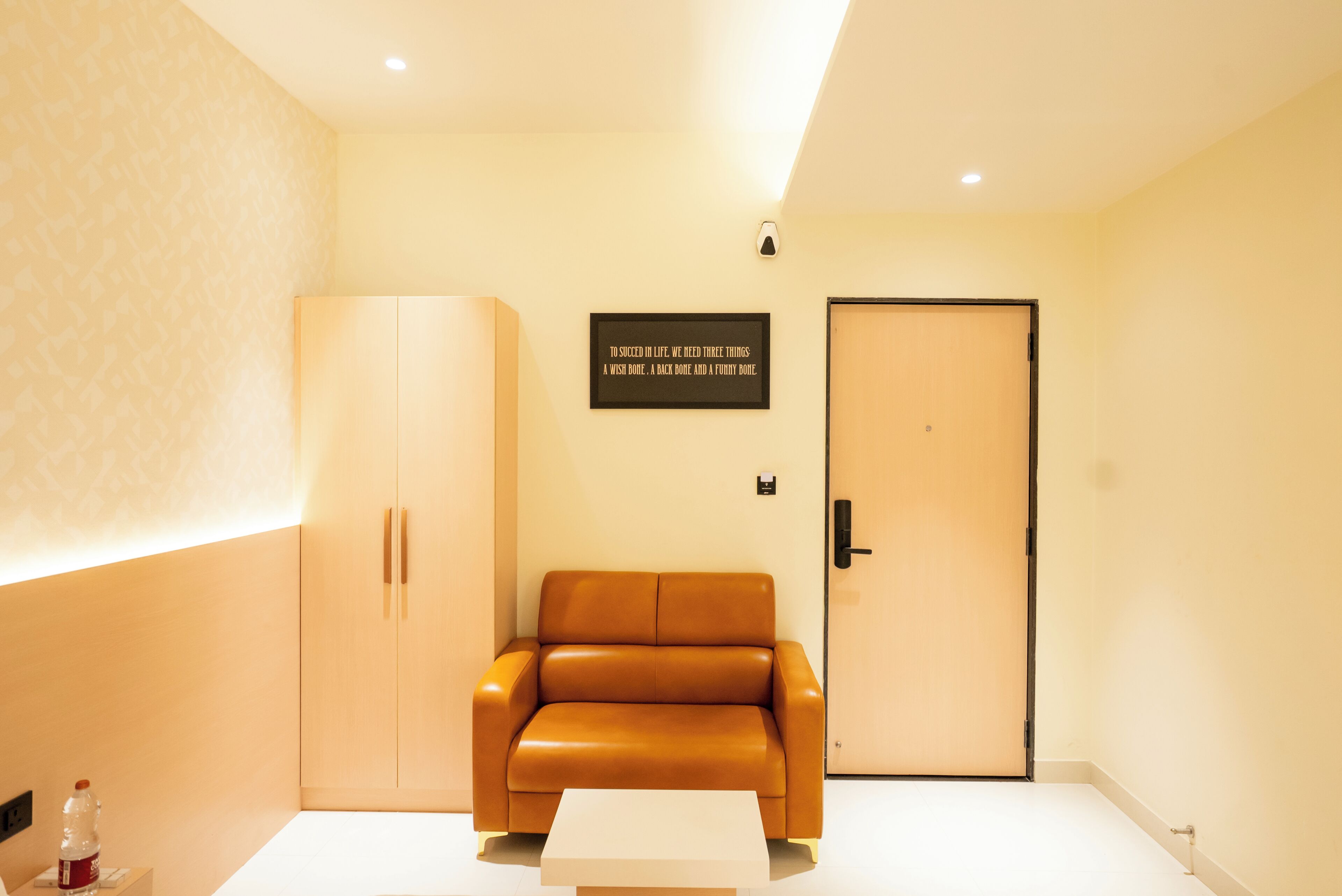 A room with a sofa, a wardrobe, a door, and a wall-mounted sign.