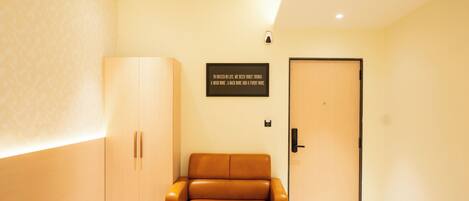 A room with a sofa, a wardrobe, a door, and a wall-mounted sign.