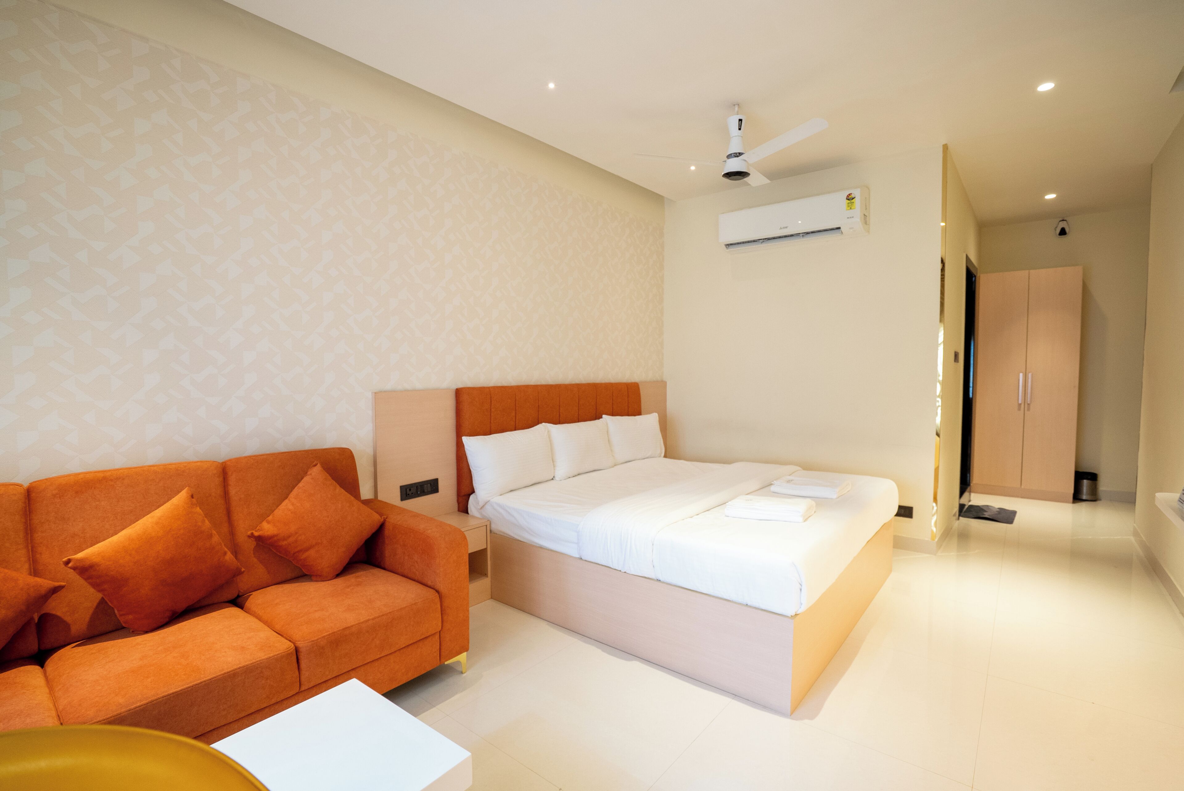 Une chambre d’hôtel comprenant un lit, un canapé, une petite table, un appareil de climatisation et une armoire.