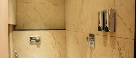 A bathroom with a toilet, a shower, and a towel rack.