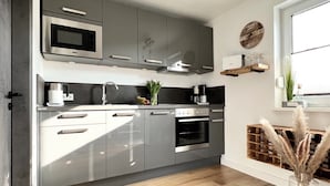 A modern kitchen with grey cabinets, a built-in oven, a microwave, and a coffee machine.