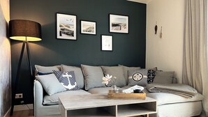 A modern living room with a dark green accent wall, a grey sofa, a wooden coffee table, and a floor lamp.