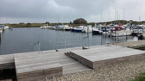 Un port de plaisance avec des bateaux amarrés, des passerelles en bois et une mouette.