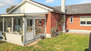 Une maison dotée d’un porche couvert, d’une façade en briques et d’une cheminée.