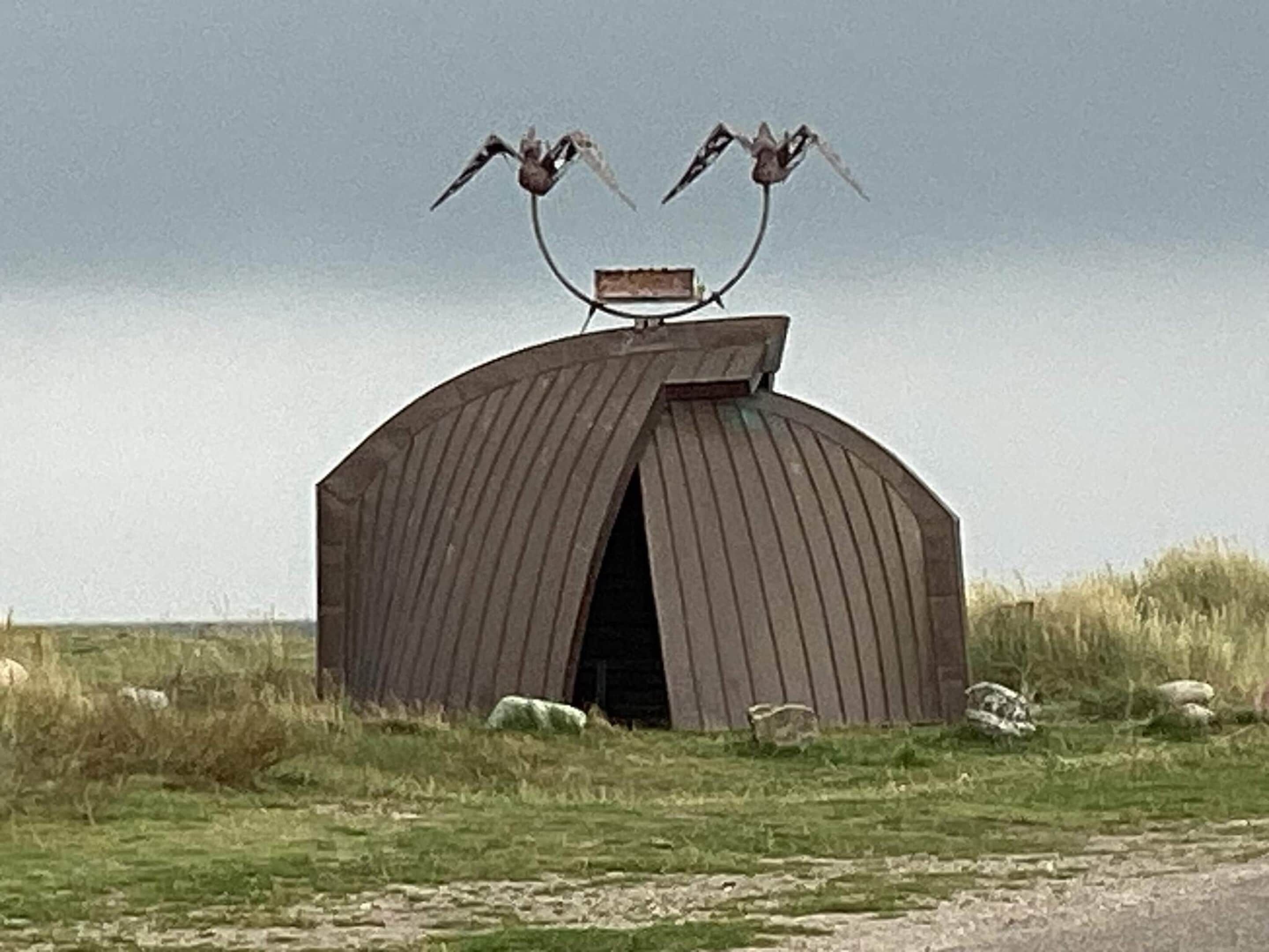 A rustic wooden structure with a curved roof and a central opening.