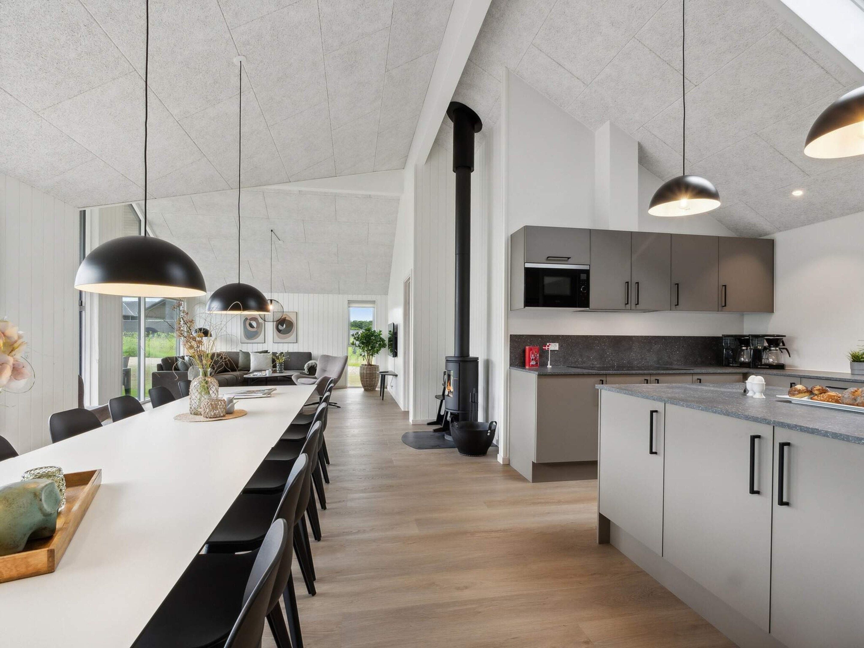 Una cocina moderna con una isla central, lámparas colgantes negras y una estufa grande.