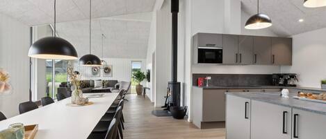 Una cocina moderna con una isla central, lámparas colgantes negras y una estufa grande.