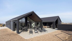 Un edificio moderno con un amplio patio y mobiliario exterior.