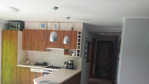 A modern kitchen with wooden cabinets, a central island, and pendant lighting. - Apartment in Sopot Near Monte Cassino Street (Sopot)