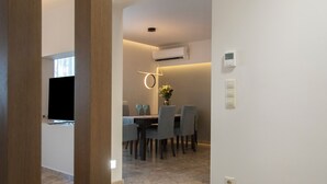 A modern dining area with a marble floor, a dining table with chairs, a vase with flowers, and a ceiling light fixture.