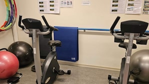 A gym with two stationary bikes, a blue mat, and exercise balls. - 2 Person Holiday Park Home in Lemvig (Lemvig)