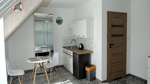 Une cuisine compacte équipée d’un évier, d’une cuisinière et d’un petit coin repas avec une table et des chaises.