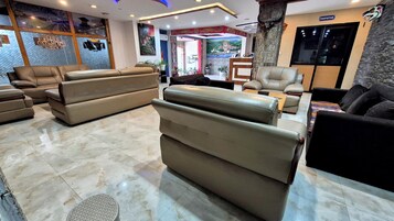 Un moderno hall de hotel con sofás de cuero, un mostrador de recepción y un ventanal grande.