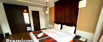 Camera d'albergo con un letto grande, un comodino, una lampada e una finestra con tende.