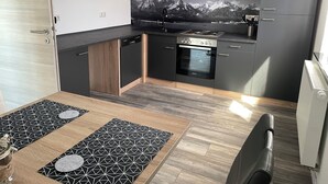 Moderni keittiö, jossa on mustat kaapit, sisäänrakennettu uuni ja astianpesukone.