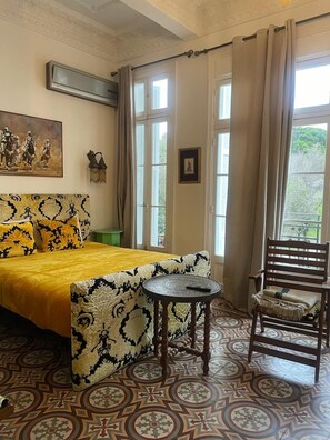 A room with a bed, a chair, a small table, and a painting on the wall. - Lalla radia (Tangier)