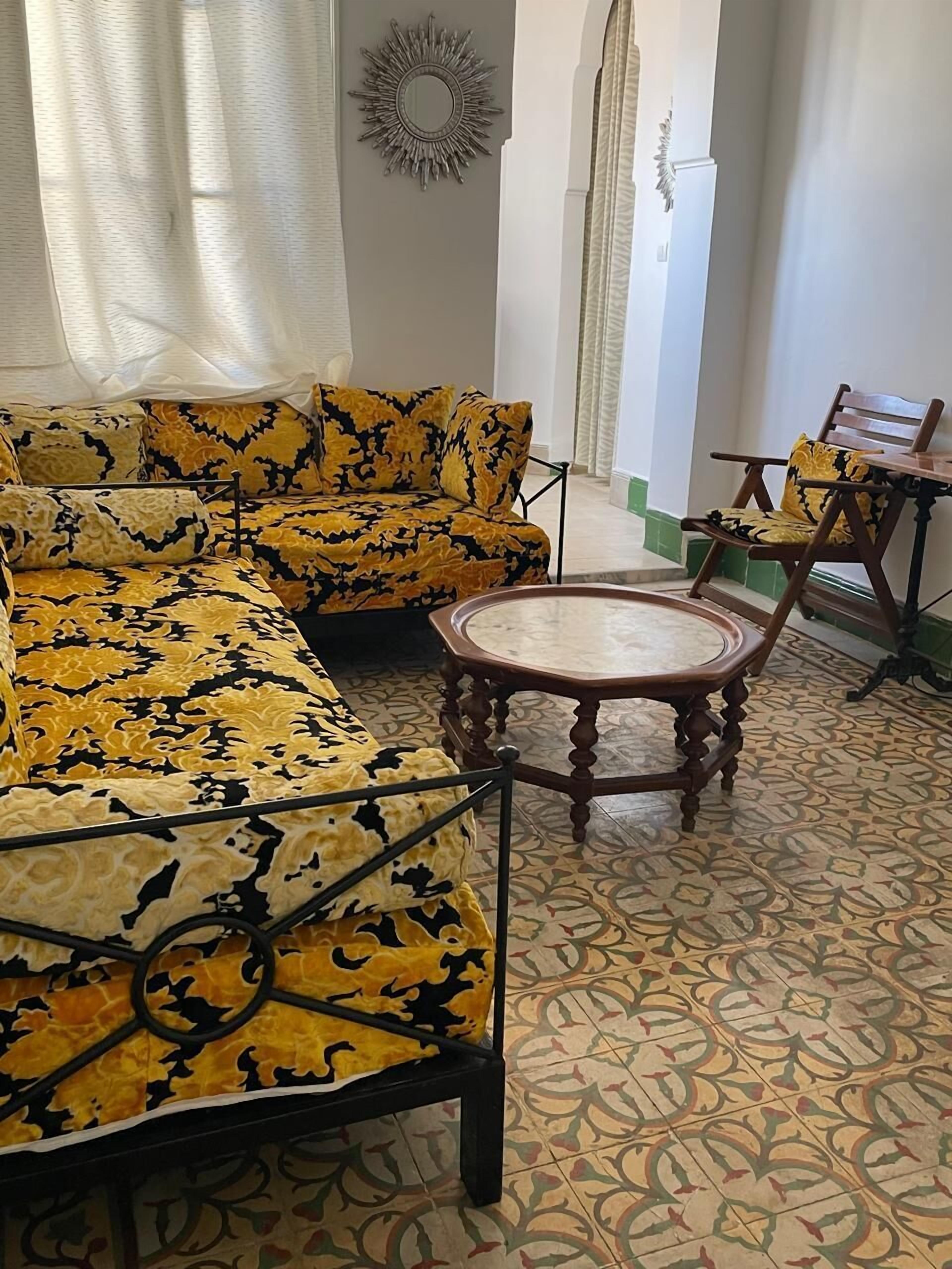 Una sala de estar con sofás estampados, una mesa redonda de madera y un piso con diseño.