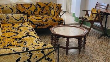 Una sala de estar con sofás estampados, una mesa redonda de madera y un piso con diseño.