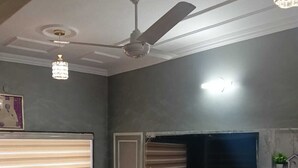 Una sala de estar moderna con un televisor de pantalla plana grande, un ventilador de techo y una chimenea de mármol.
