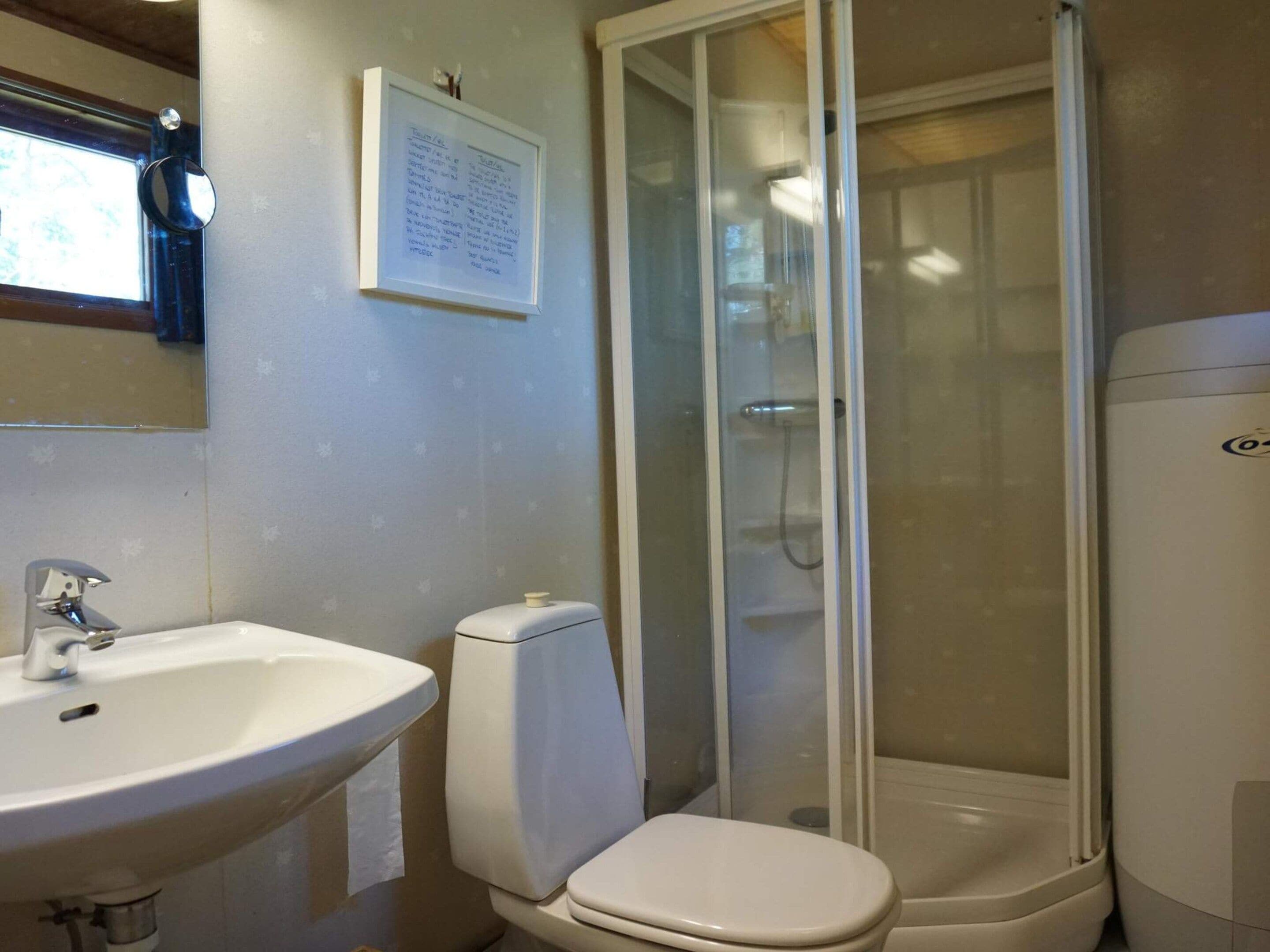 A bathroom with a white sink, toilet, and shower enclosure.